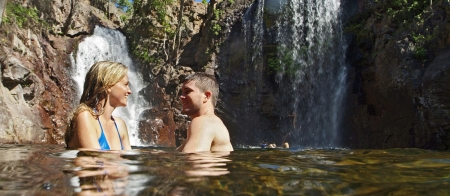 a person sitting on a rock next to a waterfall