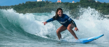 a young girl riding a wave on a surfboard in the ocean