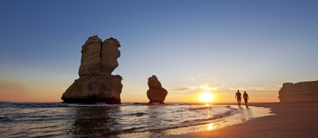 a man walking across a beach next to a body of water