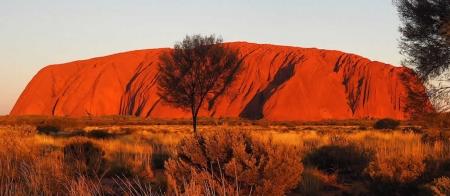 a canyon with a sunset in the background with Uluru in the background