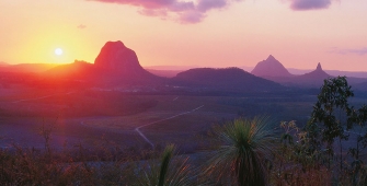 a sunset over a body of water with a mountain in the background