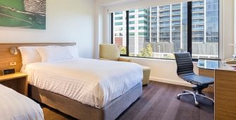 a bedroom with a bed and desk in a hotel room