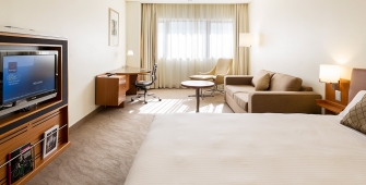 a hotel room with a flat screen tv sitting on top of a bed