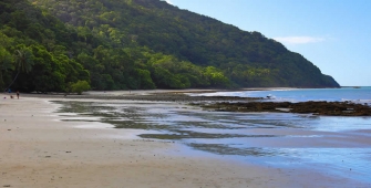 a sandy beach next to a body of water