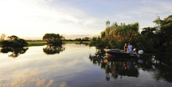 a boat floating along a river next to a body of water