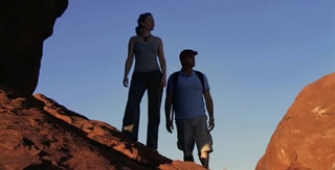 a couple of people standing on a rocky hill