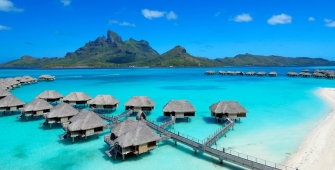 a blue umbrella next to a body of water with Bora Bora in the background