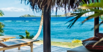 a beach with a palm tree in front of a body of water