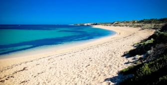 a sandy beach next to a body of water