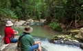 a man sitting on a rock next to a body of water