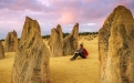 a man riding on top of a rock with Nambung National Park in the background