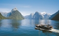 a small boat in a body of water with Milford Sound in the background