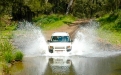 a man driving a car going down the river