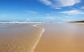 a sandy beach next to a body of water