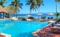 a pool next to a body of water surrounded by palm trees