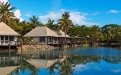 a small house in a body of water surrounded by palm trees