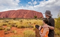 a boy standing in front of Uluru