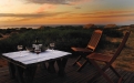 a wooden bench sitting in front of a sunset