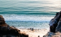 a person standing on a rocky beach next to the ocean