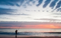 a man standing on a beach with a sunset in the background