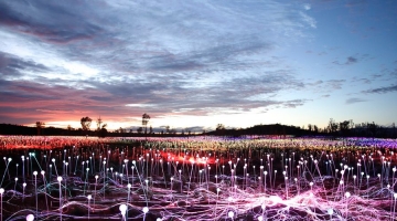 a group of people performing on stage in front of a body of water