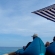 a man sitting at a beach umbrella next to a body of water