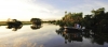 a boat floating along a river next to a body of water